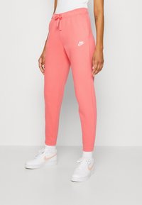 Rosa Nike sweatpants med elastisk midja och dragsko, avsmalnande ben och logotypdetalj. Kombinerat med vita sneakers och strumpor.