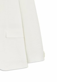 Manga de blazer blanca texturizada y parte inferior delantera con bolsillo de solapa y tres botones a juego en el puño.