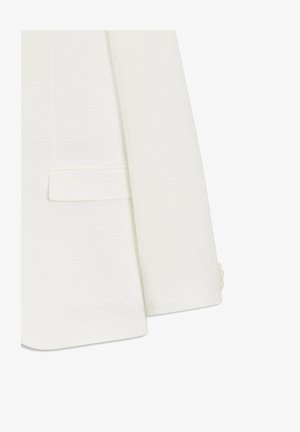 Weiße Texturiertes Blazermaterial am Ärmel und unteren Vorderteil mit Klappentasche und drei passenden Knöpfen am Ärmelabschluss.