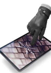 Guanto in pelle nera con superficie texturizzata, che batte su un tablet che mostra un logo e uno sfondo marrone squamato.