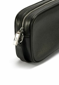 Czarna skórzana saszetka na zamek błyskawiczny z teksturowanym wykończeniem, srebrnymi elementami zamka oraz prostokątnym kształtem z zaokrąglonymi rogami.