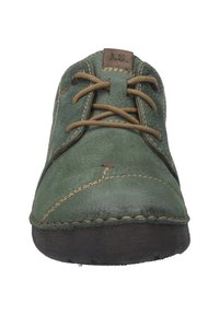 Zelená kožená bota s texturovaným povrchem, kontrastním béžovým prošíváním a hnědými tkaničkami. Čtvercový design špičky a plochá černá gumová podrážka.