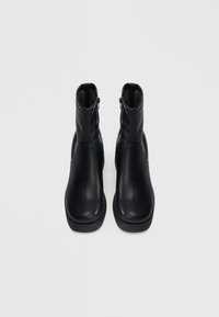 Melnas ādas potītes zābaki ar apaļu purngalu, sānu rāvējslēdzējiem un gludu tekstūru. Izturīga melna gumijas zolīte ar nelielu papēdi.