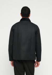 Μαύρο σακάκι με γιακά, ραφές στους ώμους και ίσια γραμμή. Διαθέτει απαλή υφή και φαίνεται από πίσω.