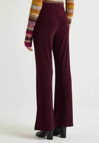 Bordeauxrote, weit geschnittene Hose aus glattem Stoff, mit elastischem Bund und dezenten Nahtdetails an den Säumen.