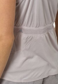 Lichtgrijze sporttop gemaakt van mesh stof, met een elastische tailleband met "adidas" branding en een comfortabele pasvorm, inclusief zijzakken.
