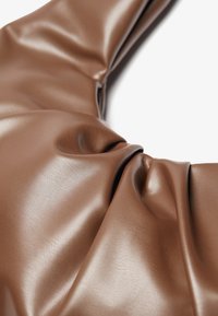 Tessuto in similpelle marrone con una texture liscia e lucida, che presenta morbide pieghe e grinze nel materiale, creando una profondità visiva.