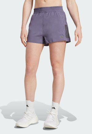 Purple athletic shorts with an elastic waistband, featuring three black stripes on the side. Styled with white footwear and socks.