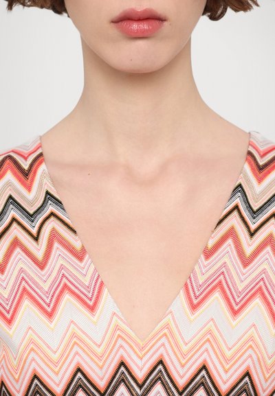 V-neck dress featuring a zigzag pattern in pink, orange, and black, with a textured woven fabric and a fitted design around the neckline.
