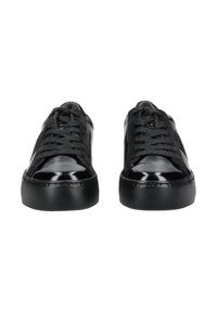 Paire de baskets basses noires brillantes avec semelles en caoutchouc texturées et lacets noirs, vues de face sur fond blanc.