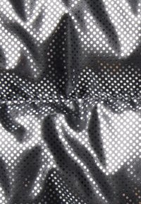 Glänzender schwarzer Nylonstoff mit einem Punktemuster und zerknitterter Textur, mit einer Naht, die horizontal über die Mitte verläuft.