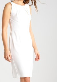 Weißes ärmelloses Kleid mit einer taillierten Silhouette, das ein dezentes plissiertes Design im Oberteil und einen glatten, strukturierten Stoff aufweist.