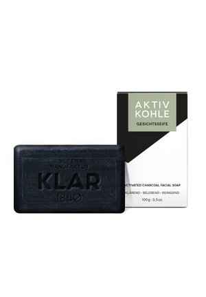 Schwarze rechteckige Seife mit eingeprägtem Schriftzug „KLAR 1840“, daneben eine schwarz-weiße Schachtel mit der Aufschrift „Aktiv Kohle“ Aktivkohle-Gesichtsseife.