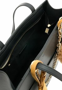 Borsa tote nera con esterno in pelle liscia, zip dorata e una catena decorativa rimovibile. L'interno presenta una tasca con zip e una morbida fodera.
