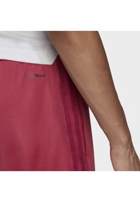 Bordowe spodenki sportowe z textured panelem po bokach, logo "AEROREADY" oraz gładkim wykończeniem, ilustrujące sportowy design.