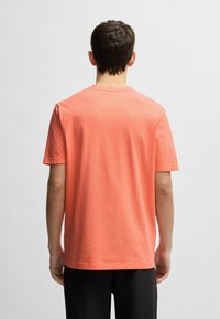 Koralfarvet bomulds t-shirt med korte ærmer, firkantet halsudskæring og sømløs ryg. Letvægtsstof med en glat overflade.