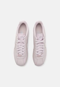 Sneaker in pelle rosa chiaro con punta arrotondata, chiusura con lacci, colletto imbottito e piccolo logo Nike sul lato e sulla linguetta.