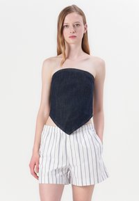 Denim stroppeløs topp med en trekantet kant, kombinert med hvite og marineblåstripete shorts med elastisk midje og lommer.