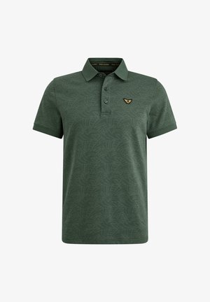Polo vert en tissu texturé, avec un motif subtil, trois boutons et un emblème doré sur la poitrine gauche.