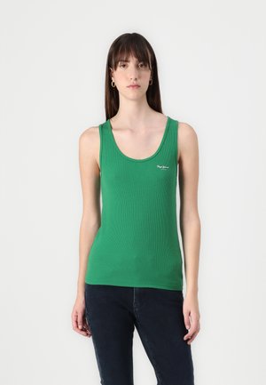 Green ribbed tank top with a scooped neckline and a small white logo on the chest, paired with dark jeans.