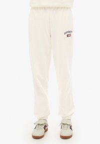 Crème kleurige joggingbroek met elastische boorden, voorzien van het "Superdry" logo en vlag borduursel op de linker dij. Gestructureerde stof.