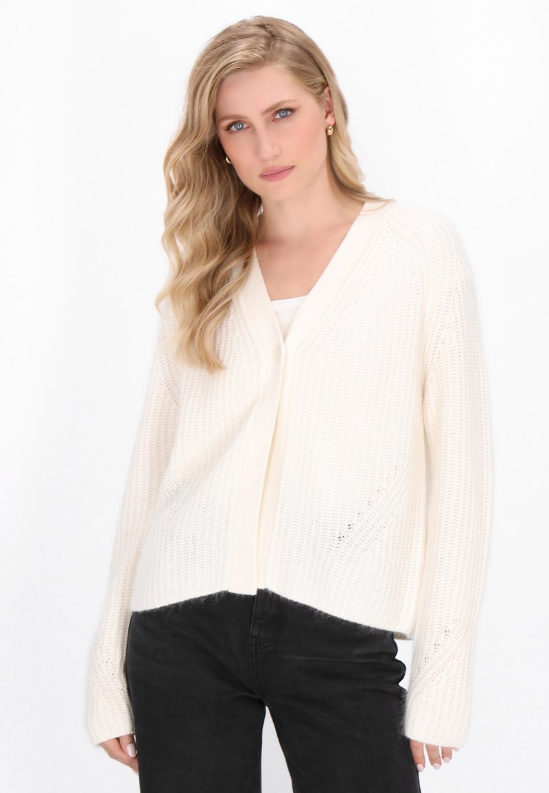 Crème-kleurige, gebreide cardigan met een V-hals, open voorkant en lange mouwen. Heeft een gestructureerde weef en een losse pasvorm.