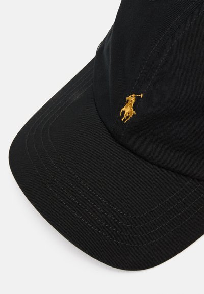 Boné de algodão preto com aba curva, apresentando um logótipo bordado em dourado na frente. A textura é suave com detalhes de costura visíveis.