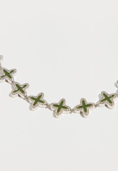 Ogrlica srebrne barve z izmeničnimi zelenimi zvezdastimi povezavami in majhnimi prozornimi dragimi kamni okoli vsakega dela, kar ustvarja teksturiran videz.