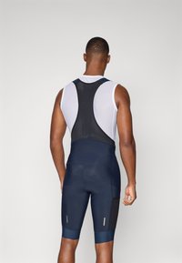 Pantalones cortos de ciclismo de color navy con parte trasera de malla, que incluyen un acolchado contorneado, acentos reflectantes y un diseño ajustado para mejorar la aerodinámica.