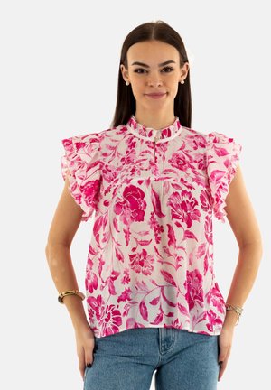 Blusa floral rosa con mangas acampanadas, con cuello alto y patrón floral vertical en tejido ligero. Combinada con jeans azules.