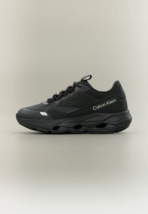 Sort Calvin Klein sneaker med tekstureret overdel, snørebånd og tyk sål med ventilationshuller på en neutral baggrund.