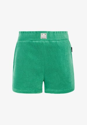 Różowa bezrękawnikowa bluzka z falbanami, w połączeniu z zielonymi szortami. Szorty mają teksturowany wygląd, a całość dopełniają brązowe sandały.