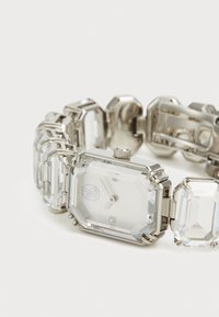 Silver wristwatch with an octagonal crystal face, clear gemstones in a linked strap, polished metal accents, and a small winding crown.