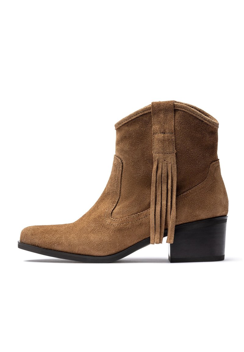 Botín de ante en marrón claro con punta puntiaguda, tacón apilado negro y detalles con flecos en la parte trasera. Textura suave en toda la superficie.
