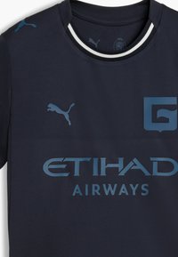 Marine atletisk t-shirt lavet af glat stof, med lyseblå logoer "Puma," "ETIHAD AIRWAYS," og en rund halsudskæring med en hvid detalje.