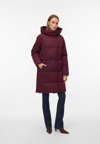 Vínově červená prošívaná bunda s vysokým límcem, boxy tvarem, prošívaným vzorem a bočními kapsami. Nositeln�á přes tmavé džíny a podpatky.