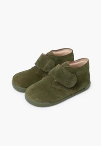 Green suede ankle boots with a Velcro strap and a textured rubber sole. Soft interior lining, simple design, and minimal detailing.