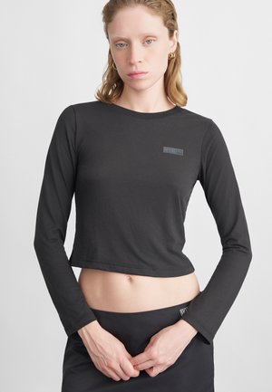 Musta lühikeste varrukatega crop-top pehmest kangast, millel on ümmargune kaelus ja väike "ROSIE" logo rinnal.