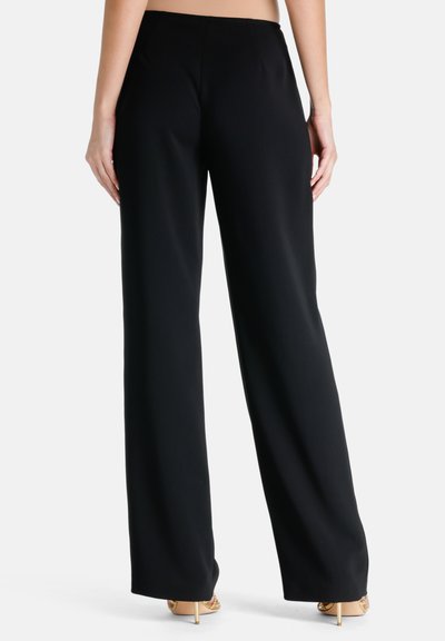 Black wide-leg trousers with a smooth texture and a clean design, featuring a high waistband and a tailored fit, worn with open-toe heels.
