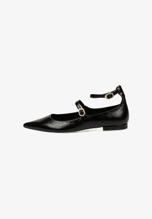Zapato plano de cuero negro con punta afilada, tira en el tobillo con hebilla dorada, textura suave y tacón bajo.