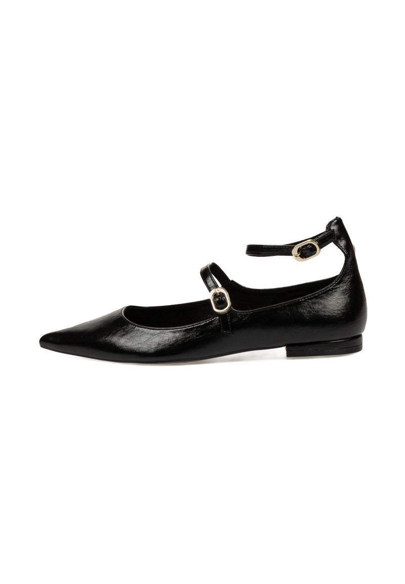 Zapato plano de cuero negro con punta afilada, tira en el tobillo con hebilla dorada, textura suave y tacón bajo.