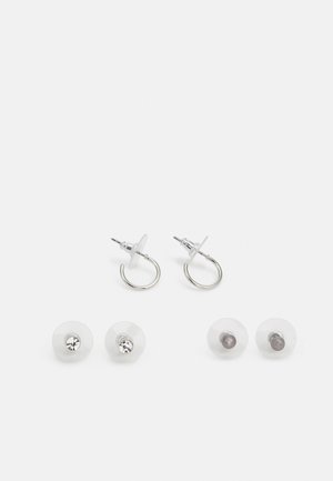 Brincos em forma de argola em tom prateado com costas de plástico transparente, apresentando dois pares de pinos intercambiáveis—um com gemas transparentes e outro cinza.