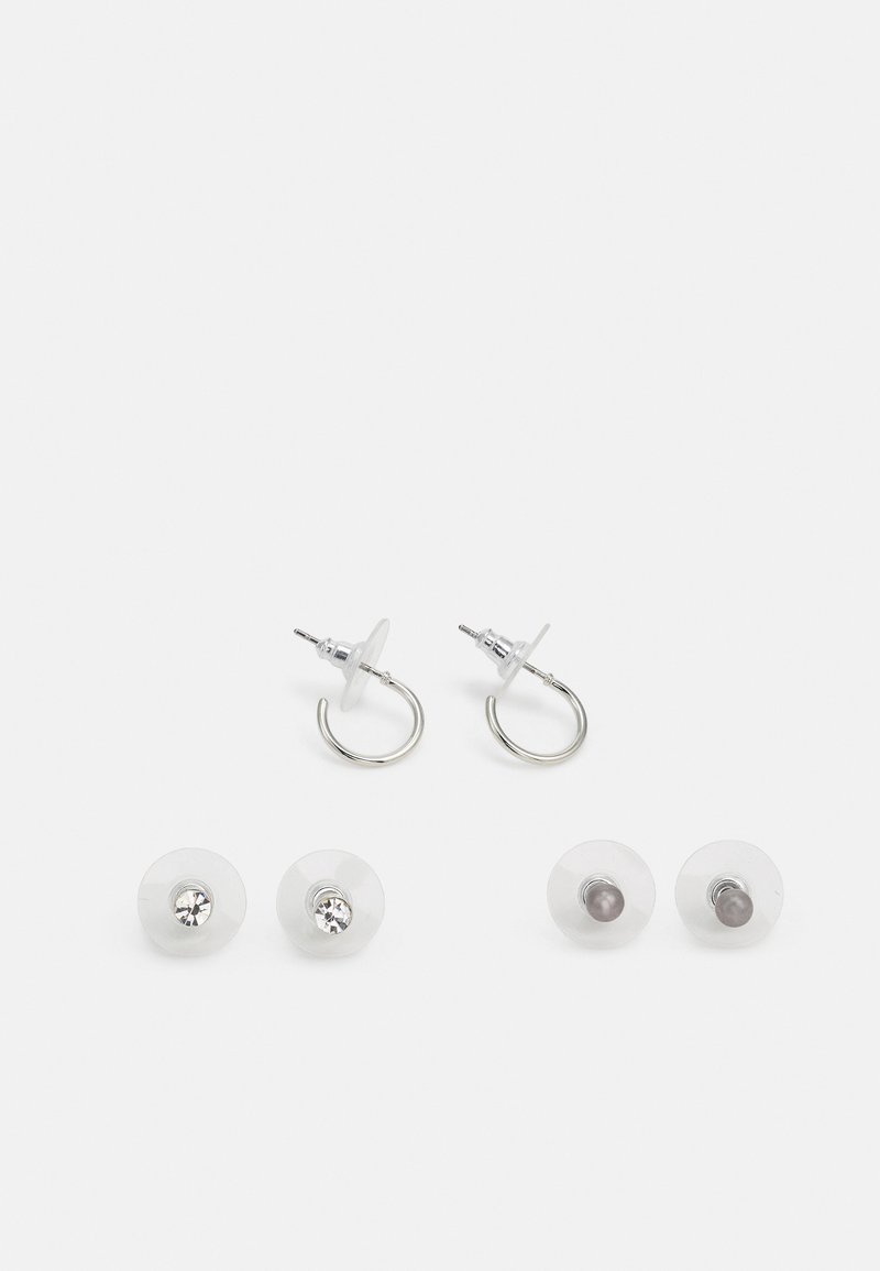 Brincos em forma de argola em tom prateado com costas de plástico transparente, apresentando dois pares de pinos intercambiáveis—um com gemas transparentes e outro cinza.