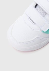 Bílá teniska s texturovaným syntetickým svrškem, zesílenou špičkou a síťovanými doplňky. Má dva suché zipy a světlou gumovou podrážku.