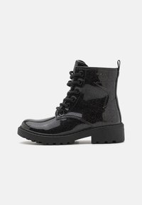 Bottines noires à lacets avec une finition brillante et pailletée, semelle en caoutchouc et détails de couture prononcés. Présente un tirant à l'arrière.