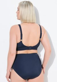 Set bikini navy con spalline regolabili, chiusura posteriore a gancio e parte inferiore a vita alta con dettagli minimi e una consistenza liscia.