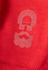 Roter Stoff mit einer dezenten, hellen Grafik eines Schädels mit einem Schnurrbart, alles in einer glatten, strukturierten Ausführung.