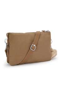 Braune Stoff-Crossbody-Tasche mit einer strukturierten Oberfläche, Reißverschluss, verstellbarem Tragegurt und einem abnehmbaren, flauschigen Pom-Pom-Zubehör.