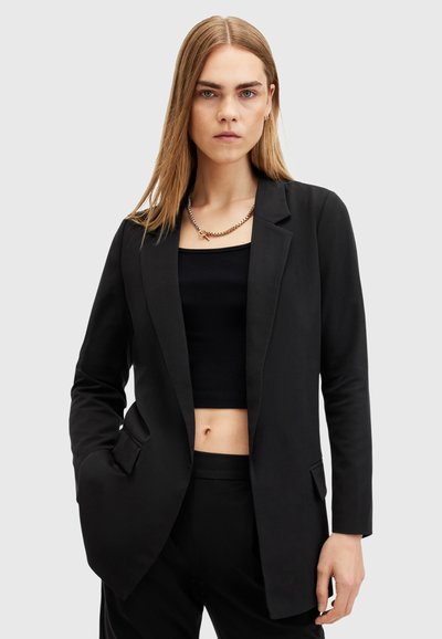 Blazer noir au design structuré, avec une fermeture à un bouton, des revers crantés et deux poches avant. Texture de tissu lisse.