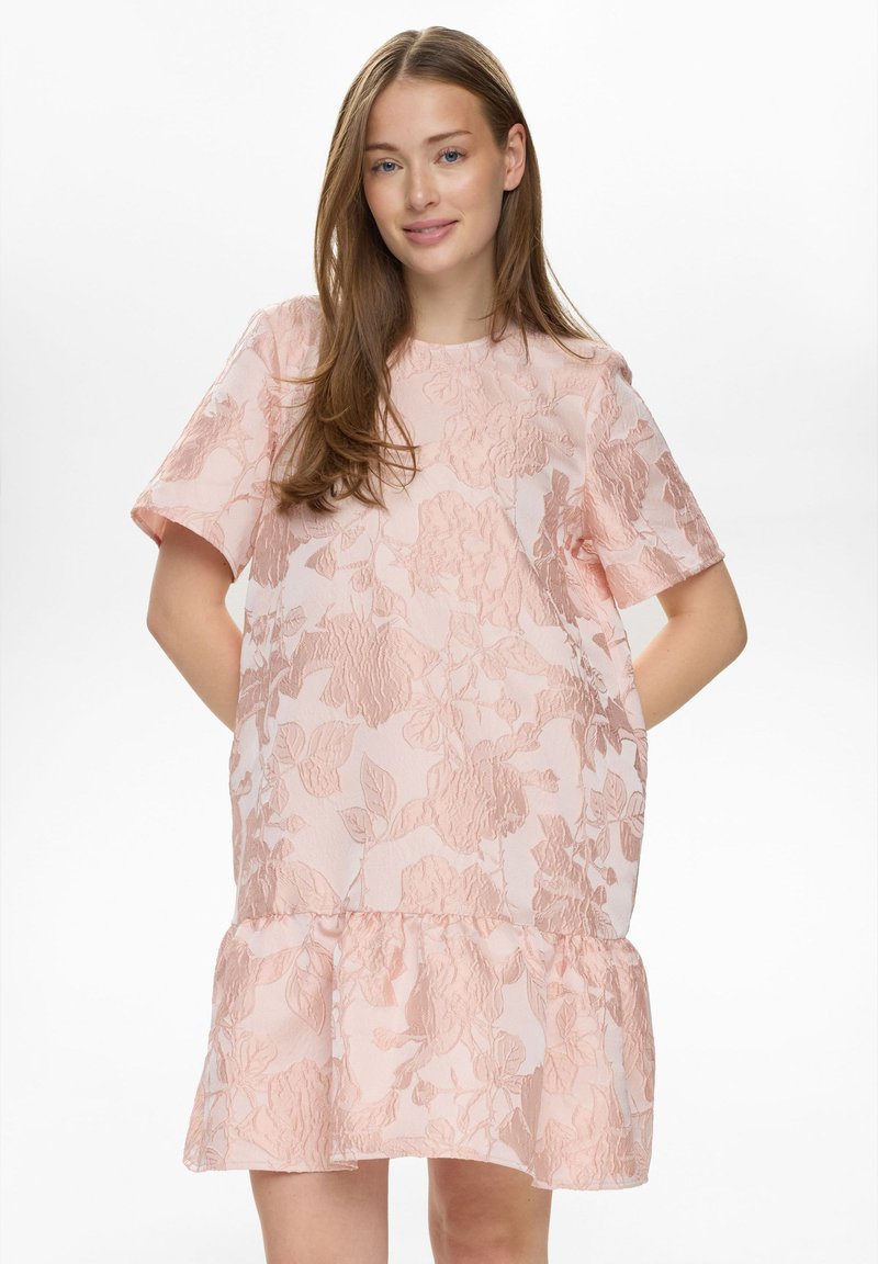 Robe rose à motif floral avec un overlay texturé, manches courtes et ourlet à volants, présentant une silhouette ample.